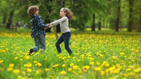 Two choldren grasping hands spinning in the field