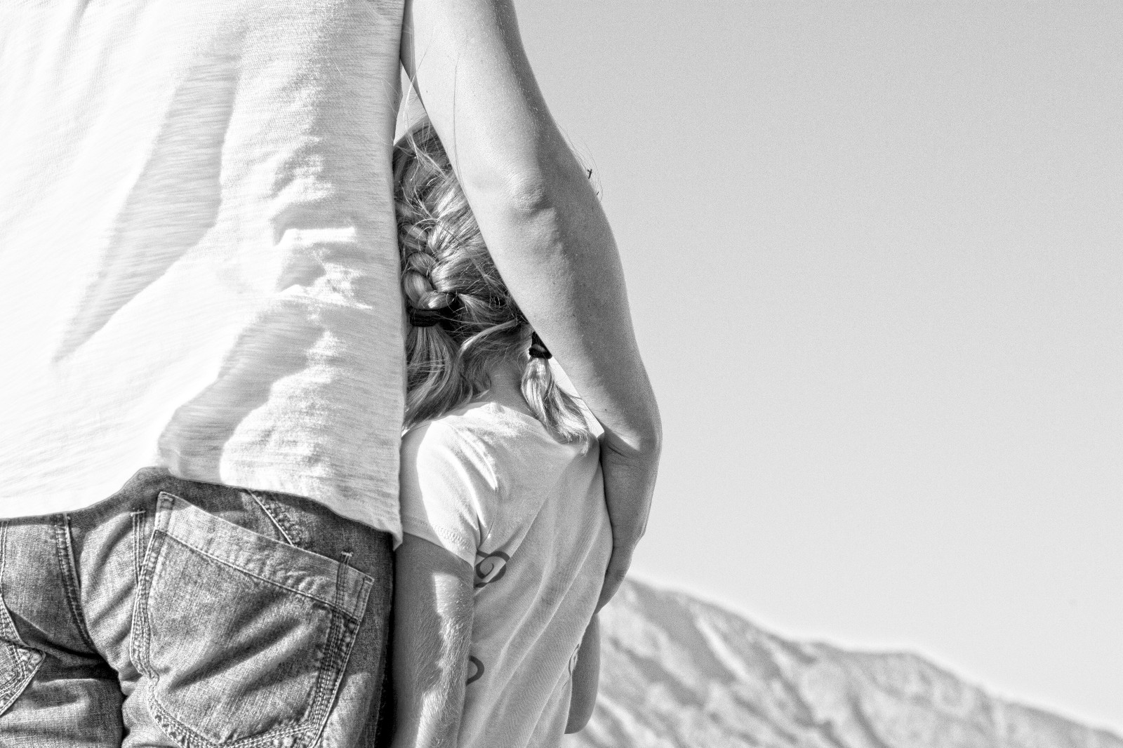 Father and daughter looking off into the distance in a half hug embrace. Black and White photo.